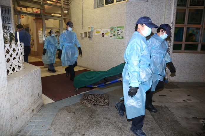 人員將死者遺體舁送殮房。