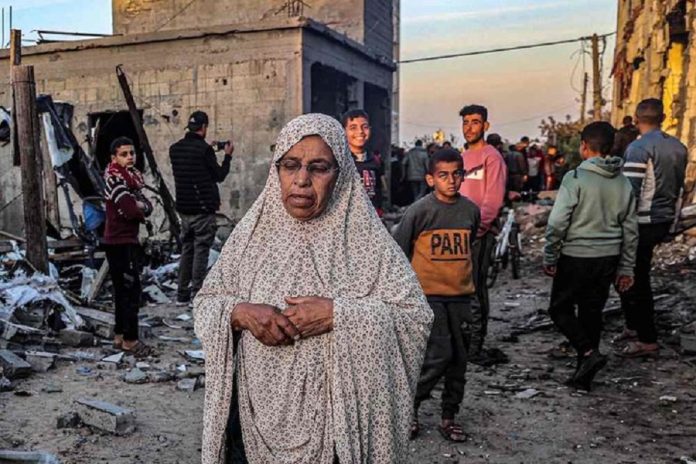 2024年2月11日,在以色列和巴勒斯坦武裝組織哈馬斯(Hamas)的衝突中,在加沙地帶南部拉法,一名老年婦女從被以色列轟炸的建築物附近走過